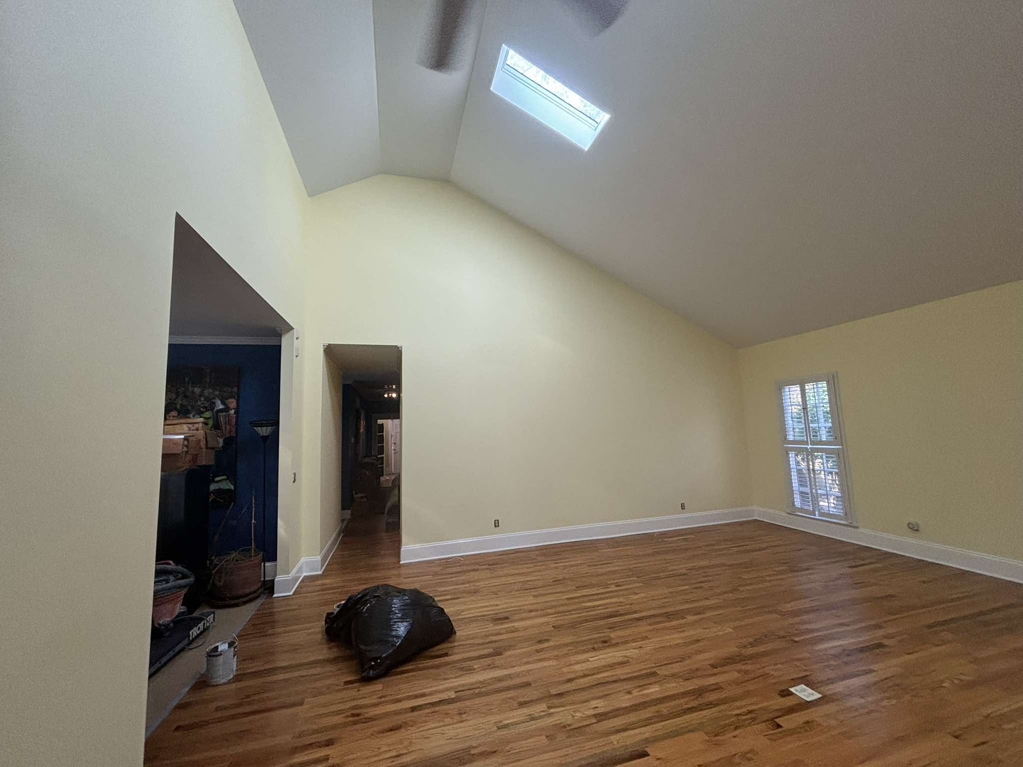 Habitación de techo alto terminada con paredes claras, molduras blancas, tragaluces y pisos de madera